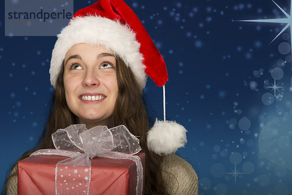 Junge Frau mit Weihnachtsmütze  mit Weihnachtsgeschenk  Portrait