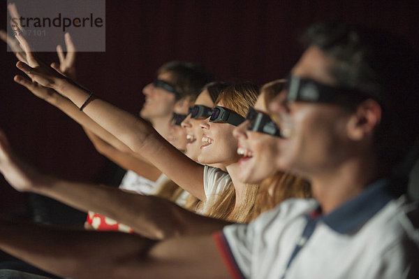 Publikum mit 3-D-Brille im Kino  Arme ausstreckend