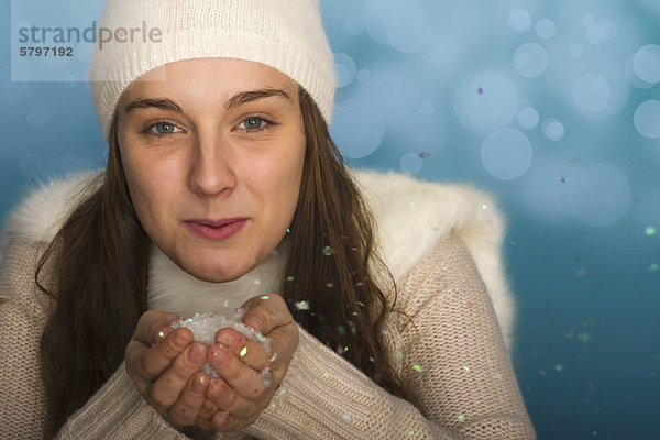 Junge Frau in Winterkleidung  hält eine Handvoll Konfetti  Porträt