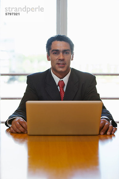 Business Executive am Schreibtisch sitzend mit Laptop  Portrait
