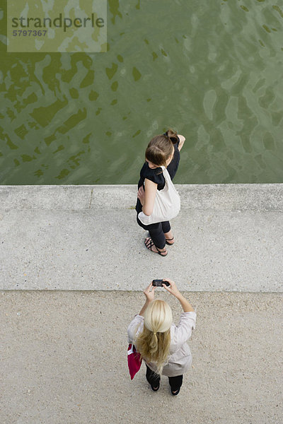 Junge Frau fotografiert Freundin mit Handy  erhöhte Ansicht