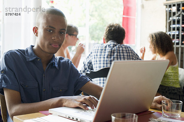 Junger Mann mit Laptop im Café