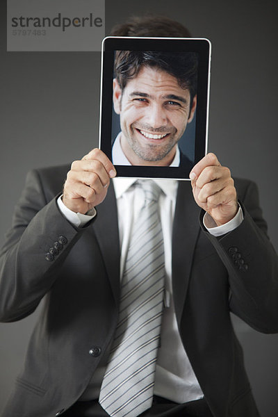 Mann mit lächelndem Foto vor dem Gesicht