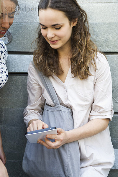 Junge Frau zeigt digitales Tablett einem Freund