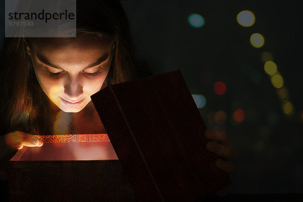 Junge Frau beleuchtet mit Licht aus der Geschenkbox