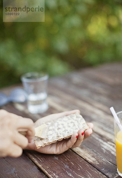 Nahaufnahme der Hand der Frau  die Butter auf Toast streicht