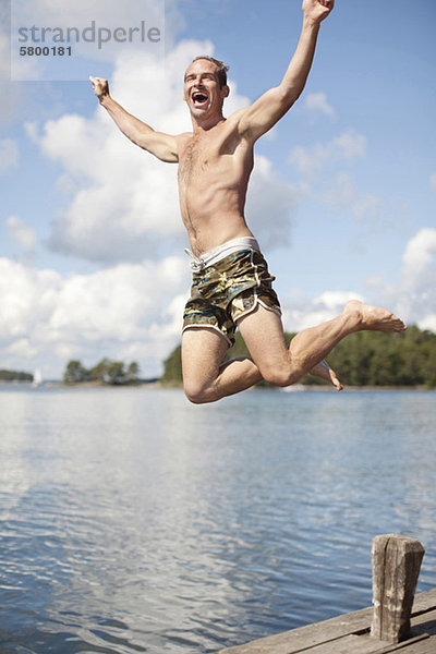 Aufgeregter reifer Mann springt in den See.