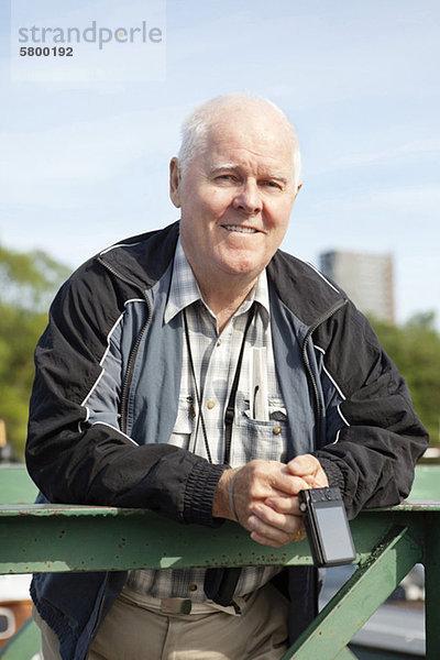 Porträt eines aktiven älteren Mannes mit Kamera im Freien