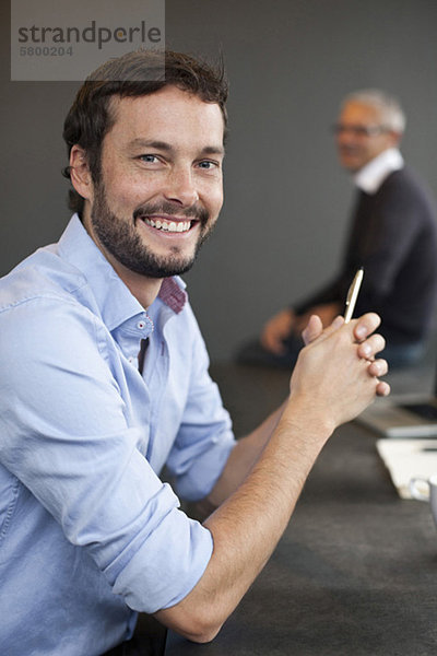 Porträt eines lächelnden Geschäftsmannes mit Kollegen im Hintergrund