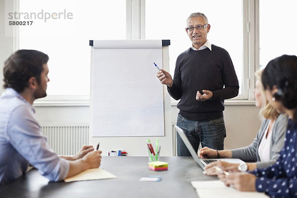 Geschäftsmann mit Whiteboard während des Meetings  der seinen Kollegen erklärt.