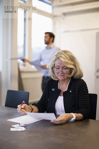Senior Geschäftsfrau prüft Dokument im Büro