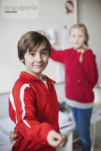 Porträt eines lächelnden Jungen mit Mädchen im Hintergrund