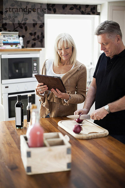 Paar in der Küche mit digitalem Tablett für Rezept und Kochmahlzeit