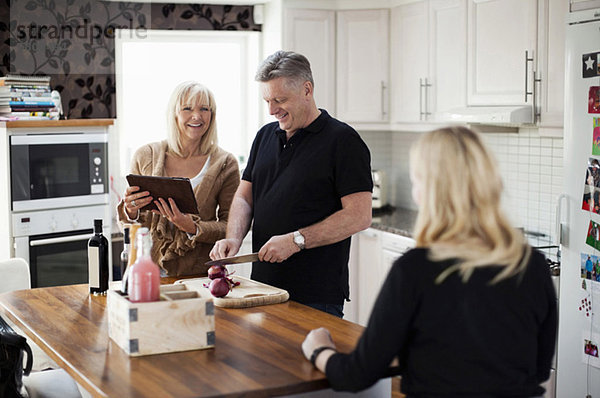 Lächelndes Paar in der Küche mit digitaler Tablette für Rezept und Kochmahlzeit