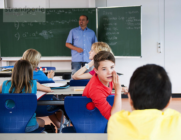 Junge flüstert im Klassenzimmer