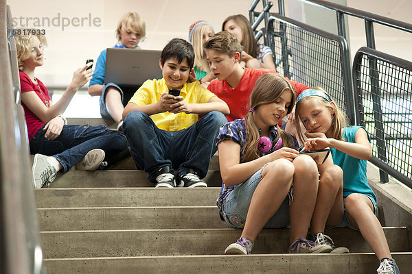 Schüler benutzen drahtlose Technologien auf einer Treppe