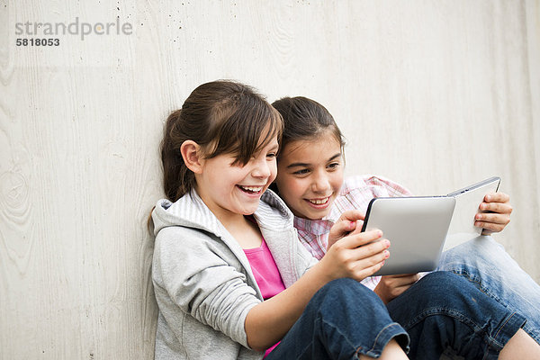Zwei fröhliche Mädchen mit einem Tablet PC