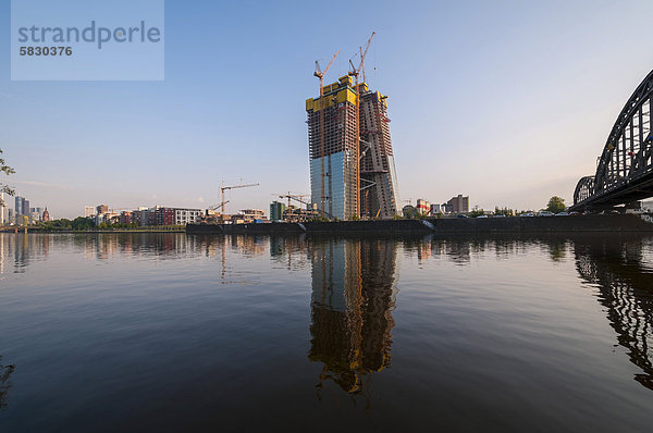 Neubau der Europäischen Zentralbank  EZB  bei Sonnenaufgang auf dem Gelände der ehemaligen Großmarkthalle mit Baukränen und der Deutschherrnbrücke im rechten Vordergrund  Frankfurt am Main  Hessen  Deutschland  Europa  ÖffentlicherGrund