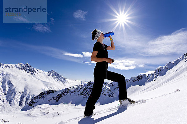 Skitourengeherin trinkt aus Flasche  Sonnenschein  Kühtai  Stubaier Alpen  Nordtirol  Tirol  Österreich  Europa