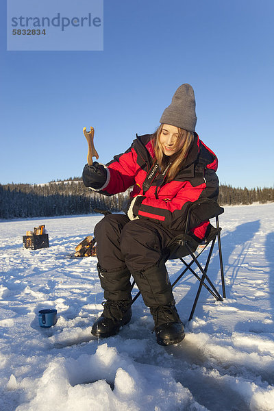 Junge Frau beim Eisfischen  Hidden Lake in der Nähe von Whitehorse  Yukon Territory  Kanada