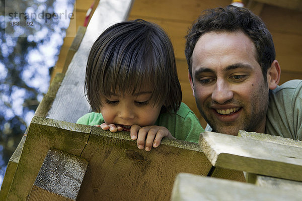 Vater und Sohn sitzen im Baumhaus