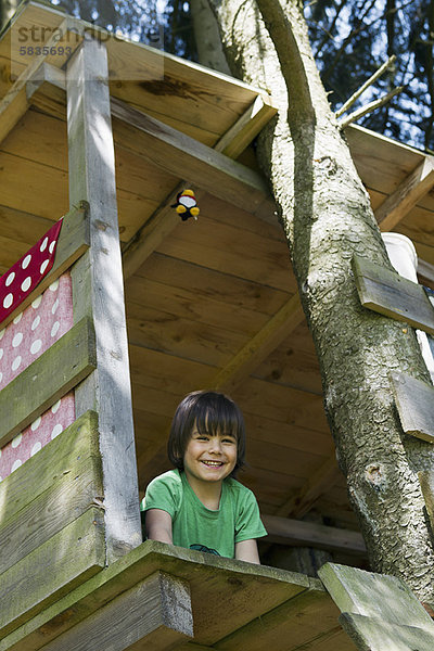 Lächelnder Junge im Baumhaus sitzend