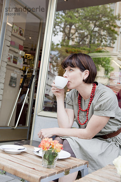 Frau beim Kaffeetrinken im Straßencafé