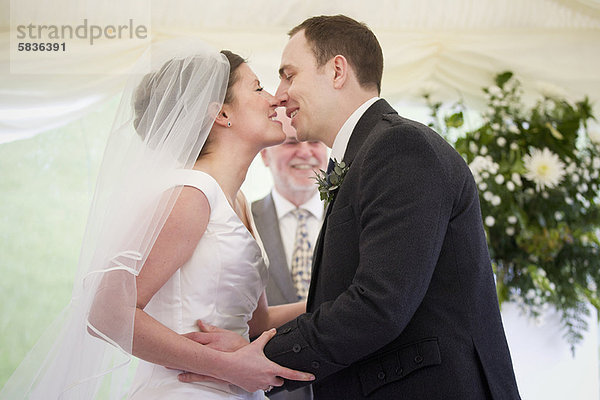 Neuvermähltes Paar küsst sich bei der Hochzeit