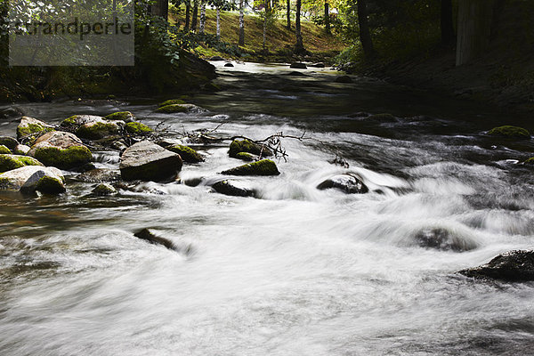 Verschwommener Blick auf den über Felsen rauschenden Fluss