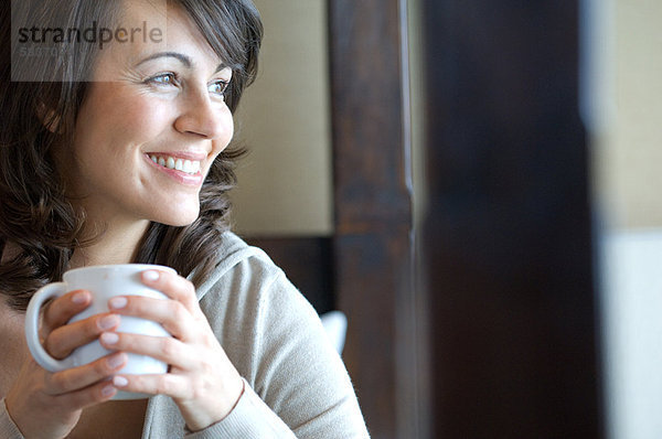 Lächelnde Frau bei einer Tasse Kaffee