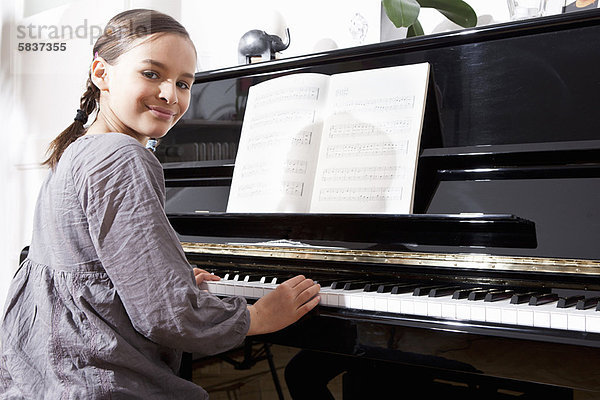 Lächelndes Mädchen beim Üben am Klavier