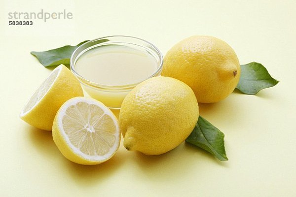 Ein Schälchen Zitronensaft und frische Zitronen