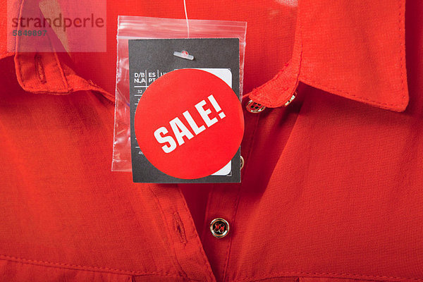 Verkaufsschild auf roter Bluse