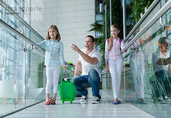 Vater und Töchter mit Gepäck am Flughafen