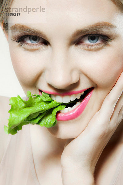 Junge Frau beißt Salat