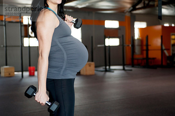 Schwangere junge Frau mit Handgewichten