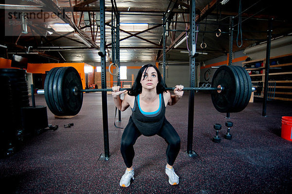 Schwangere junge Frau Gewichtheben mit Langhantel