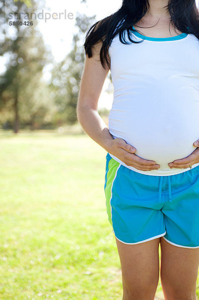 Schwangere junge Frau berühren Magen  Vorderansicht