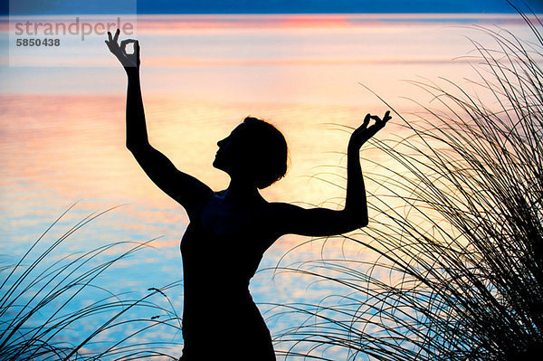 Frau tanzt bei Sonnenuntergang