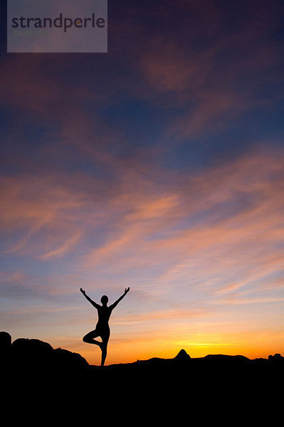 Junge Frau beim Yoga in der Wüste  Silhouette