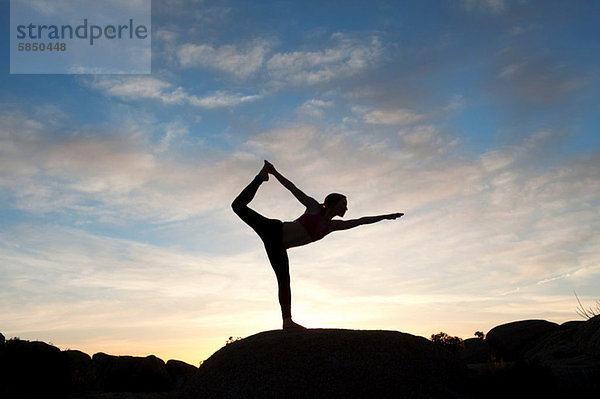 Junge Frau in Tänzerpose in der Wüste  Silhouette