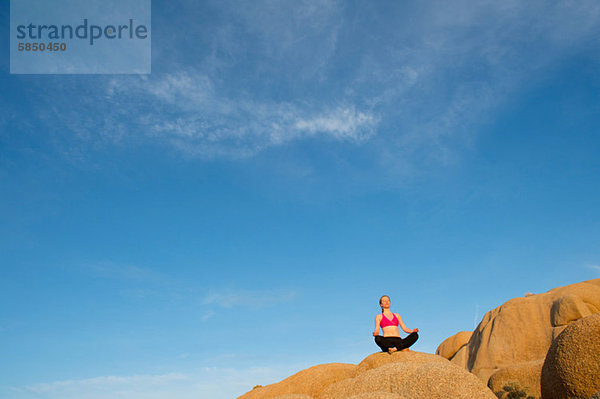 Junge Frau sitzt auf Wüste Felsen meditieren