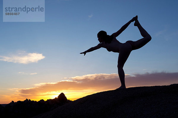 Junge Frau in Tänzerpose in der Wüste  Silhouette