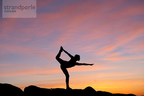 Junge Frau in Tänzerpose in der Wüste  Silhouette