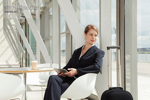 Geschäftsfrau am Flughafen sitzend mit digitalem Tablett  Portrait
