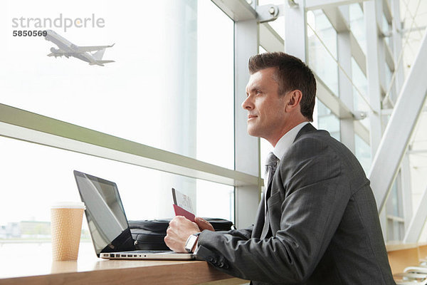 Geschäftsmann mit Laptop am Flughafen