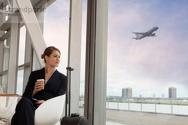 Geschäftsfrau trinkt Kaffee am Flughafen