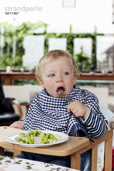 Junge  17 Monate  mit Lätzchen  isst Kiwistücke