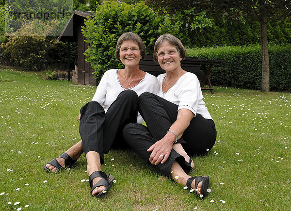 Zwei rüstige Zwillingsschwestern sitzen im Garten