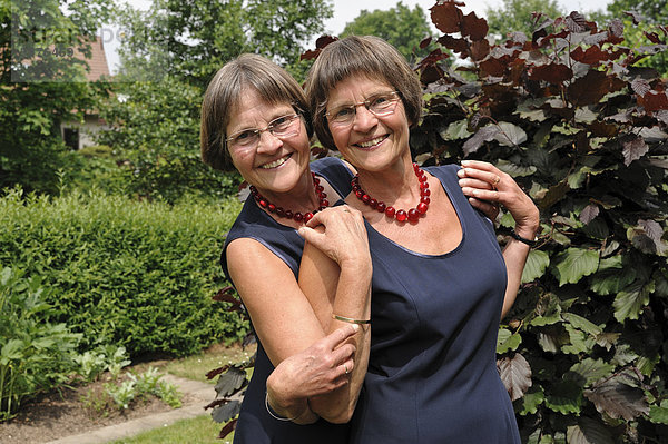 Zwei rüstige Zwillingsschwestern  gleich gekleidet  Portrait